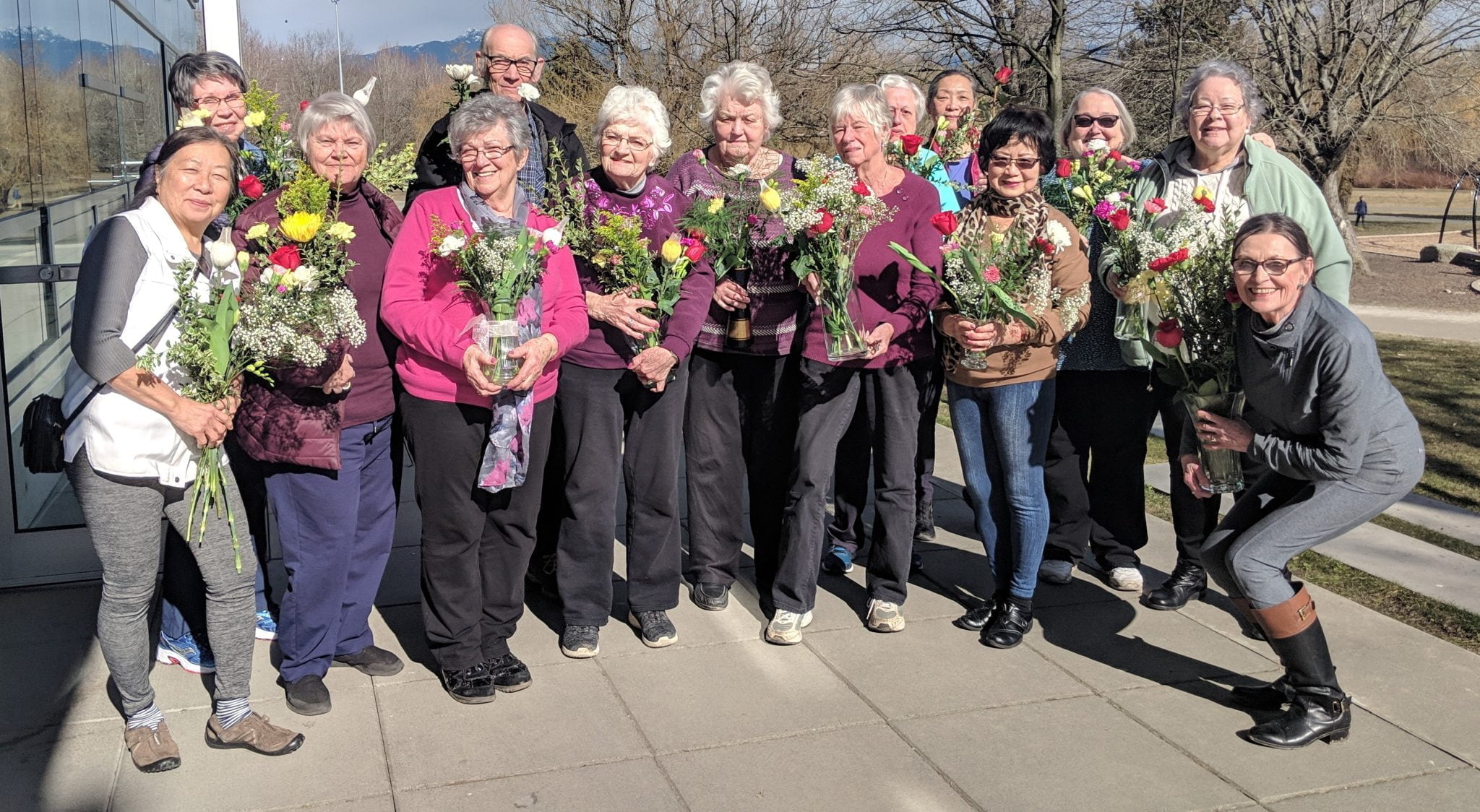 a group photo of Trout Lake seniors holding floral arrangements outside in the sun