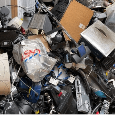 Image of various electronic waste including old laptops and corded appliances. Credit: John Cameron via Unsplash