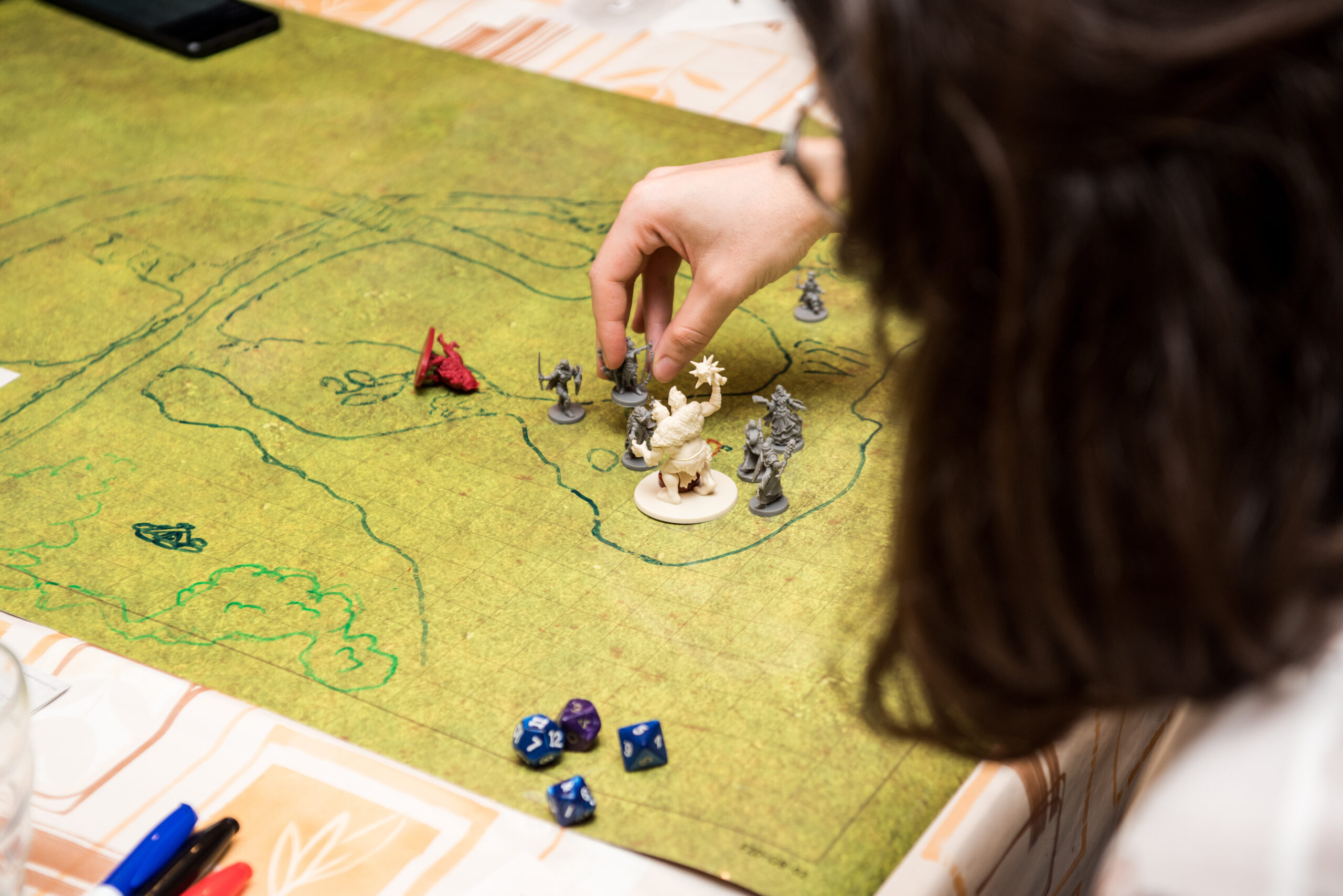 Girl with glasses playing role game dungeons and dragons, miniatures and dices on the green field. Stock photo.